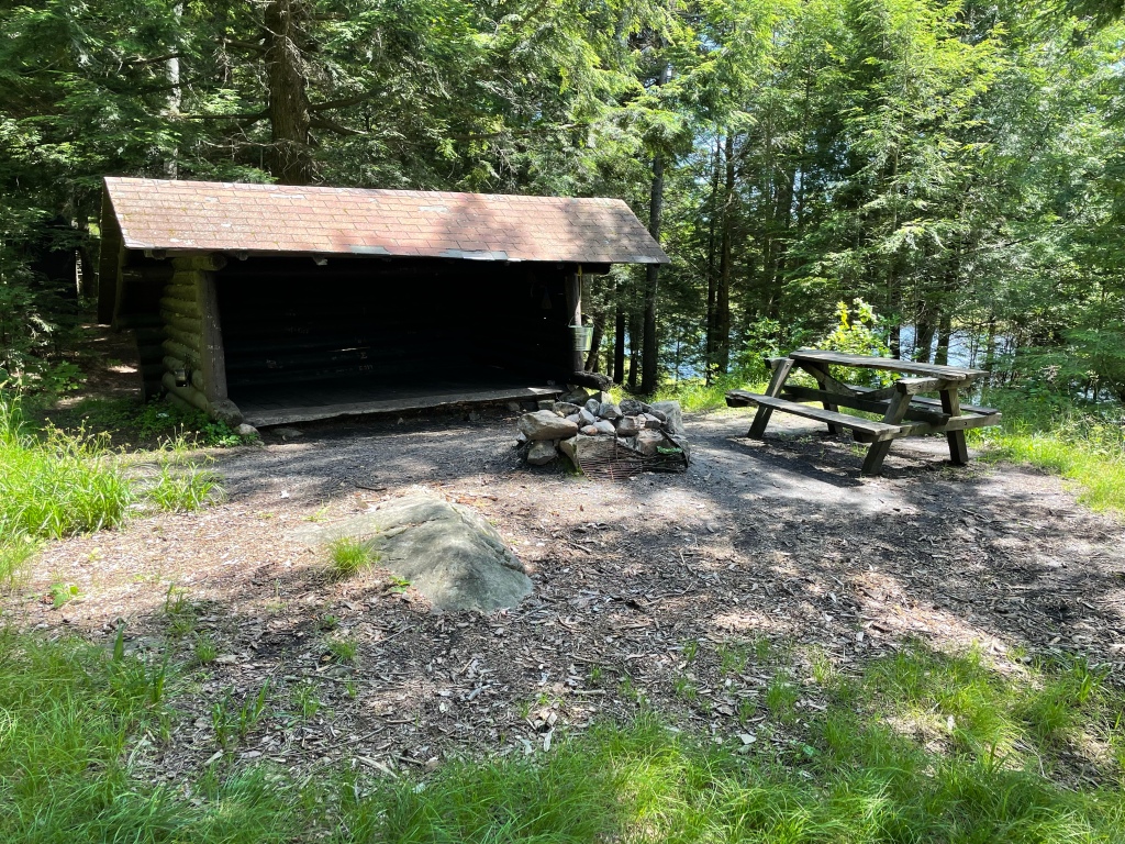 A lean-to, fire pit, and picnic table.