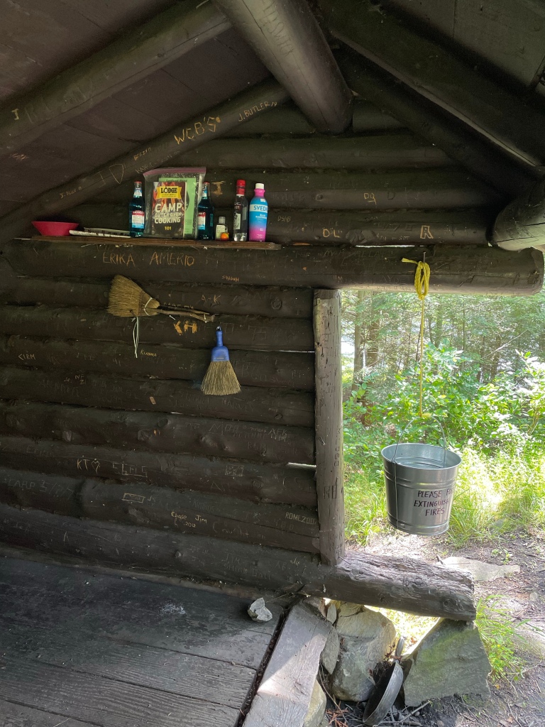 Various camping supplies are inside the lean-to, along with a journal.